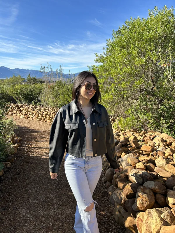 Ridhima smiling in the sunshine on a garden path, with mountains in the distance.